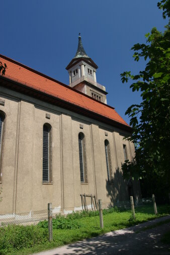 Gotteshaus unter blauem Himmel, rechts ein Baum.