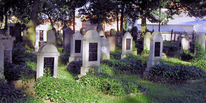 Foto: Geschützte Grabmale auf dem Friedhof Alach © Stadtverwaltung Erfurt Teilansicht eines Grabfeldes mit geschützten Grabmalen. Die stehenden Steine zeichnen sich durch eine gewisse Einheitlichkeit aus, Muschelkalk mit Rundbogenabschluss und schwarzer Namensplatten.