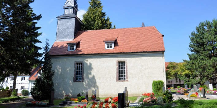 Hell verputzte Kirche mit zwei Fensten im Kirchenschiff, mit Ziegeln gedeckt. Aus dem Dach kommender Kirchturm, mit Schiefer verkleidet und vierseitigem giebelähnlichem Abschluß und Wetterfahne.