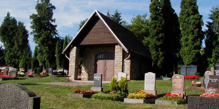 Außenansicht Trauerhalle, im Vordergrund Gräber