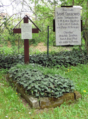 Altes, mit Efeu bedecktes Grab, dessen Grabmal ein hölzernes Kreuz ist