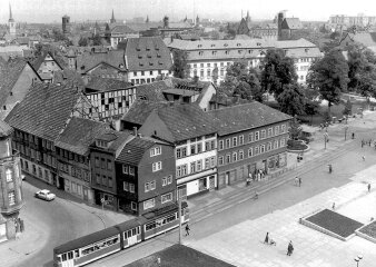 Schwarz-Weiß-Aufnahme einer Häuserzeile mit Straßenbahn