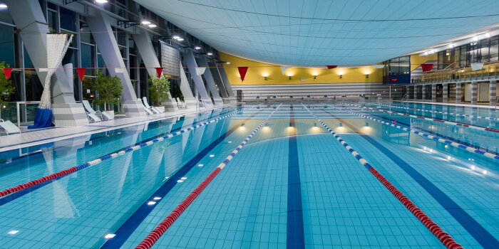 Ein Schwimmbecken in einer Schwimmhalle. Darin sind Bahnen für Schwimmer gezogen.