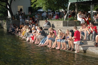 Besucher des Krämerbrückenfestes sitzen am Ufer der Gera