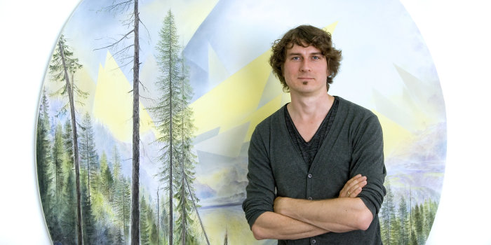 Der Künstler Wieland Payer, 2016 Junger Mann mit verschränkten Armen vor einem runden Bild.