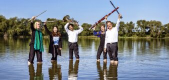 Foto: Bläserquintett „Windstärke 5“ © Theater Erfurt/Lutz Edelhoff fünf Leute mit Blasinstrumenten mit den Füßen im Wasser eines Sees stehend