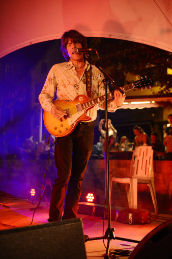 Foto: John Idan © Denise Truscello Mann mit Gitarre vor einer Bar