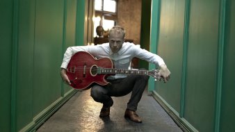 Foto: Rotem Sivan © Rotem Sivan Mann mit Gitarre auf dem Schoß in einem Flur