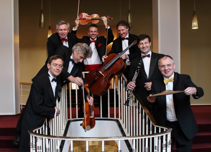 Neues Salonorchester Leipzig sieben Musiker im schwarzen Anzügen mit ihren Instrumenten auf einer Treppe