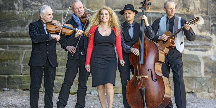 Foto: The String Company © The String Company Die 5 Musiker mit ihren Instrumenten vor der Mauer der Peterskirche