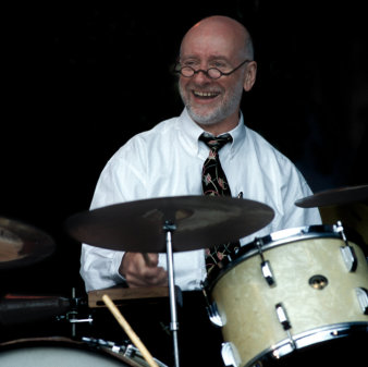 Foto: Trevor Richard New Orleans Trio © Trevor Richard reiefer Mann in weißem Hemd mit Krawatte am Schlagzeug
