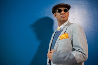 Foto: Raul Midón © Raul Midón der Künstler im grauen Anzug vor blauer Wand