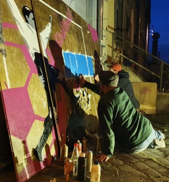 Zwei Männer besprühen eine Graffito-Wand
