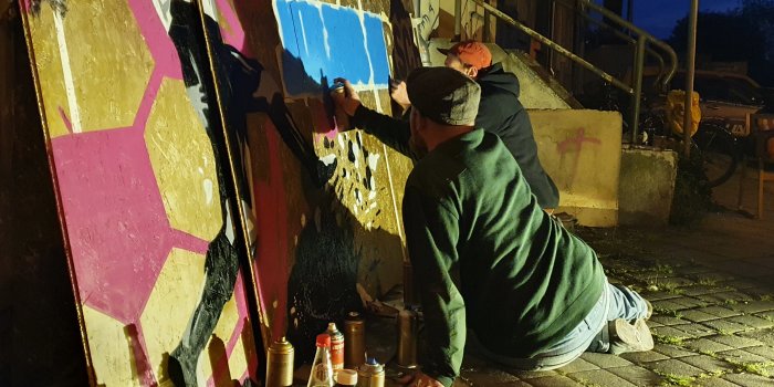 Zwei Männer besprühen eine Graffito-Wand