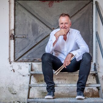 Auf Treppe sitzender Mann mit Trommelstöcken in der Hand 