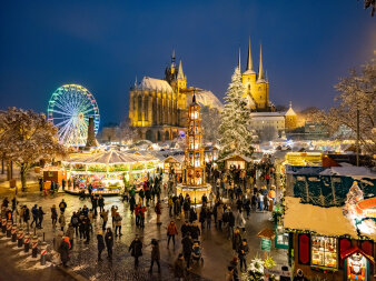 Der Erfurter Weihnachtsmarkt mit seinen Hütten und Schaustellern vor der Kulisse von Dom und Severi in den Abendstu