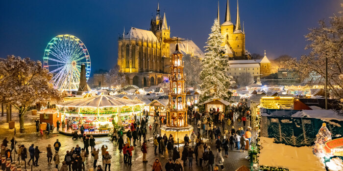Der Erfurter Weihnachtsmarkt mit seinen Hütten und Schaustellern vor der Kulisse von Dom und Severi in den Abendstu