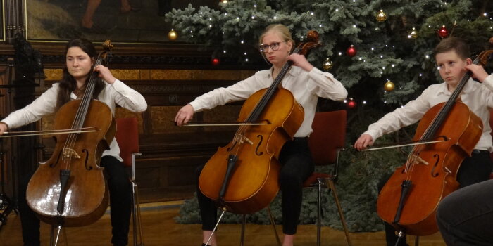 Foto: Weihnachtskonzert der Musikschule Erfurt © Stadtverwaltung Erfurt 3 junge Cellospieler vor dem Weihnachtsbaum im Rathausfestsaal.