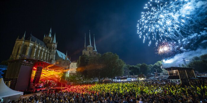 Feuerwerk auf dem Domplatz mit vielen Menschen und beleuchteter Bühne