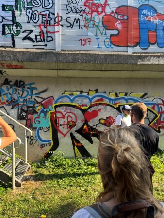 Drei Personen vor einer Wand mit Graffiti