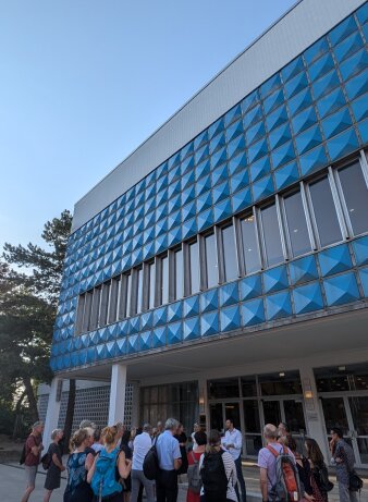 Mehrere Personen vor einen Haus mit blauen Karos an der Fassade