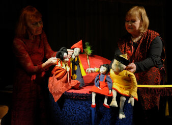 zwei Frauen spielen ein Puppentheater mit vier Figuren