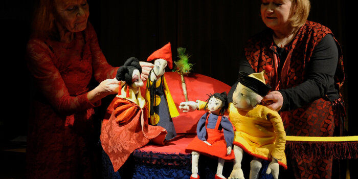 zwei Frauen spielen ein Puppentheater mit vier Figuren