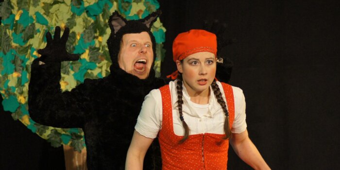 Foto: Creme Brühlee 2025: Rotkäppchen © Theater im Palais Schauspielszene aus Rotkäppchen mit Rotkäppchen und dem Wolf