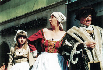 Marktvoigt, Marktweib und ihre Tochter im Kostüm um 1500 auf der Bühne vor einem Haus am Bendiktsplatz