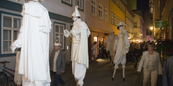 Stelzenläifer ganz in Weiß auf der Krämerbrücke bei Nacht