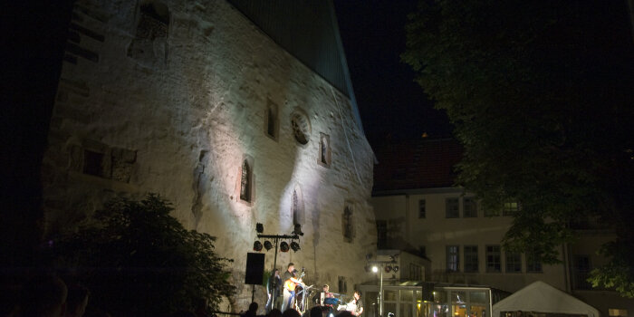 vor den Mauern der alten Synagoge bei Nacht, spielen Musiker auf einer Bühne