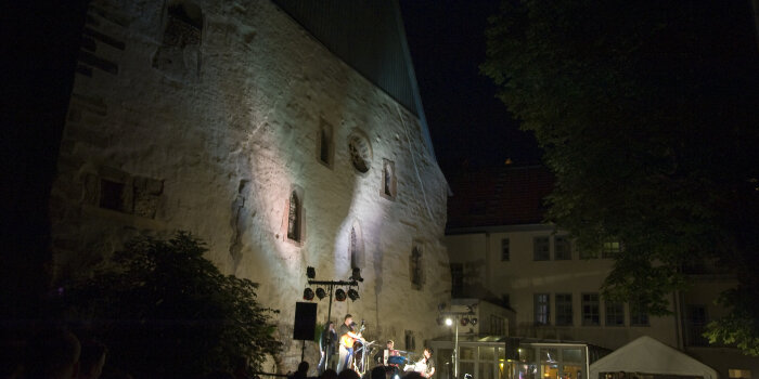 vor den Mauern der alten Synagoge bei Nacht, spielen Musiker auf einer Bühne