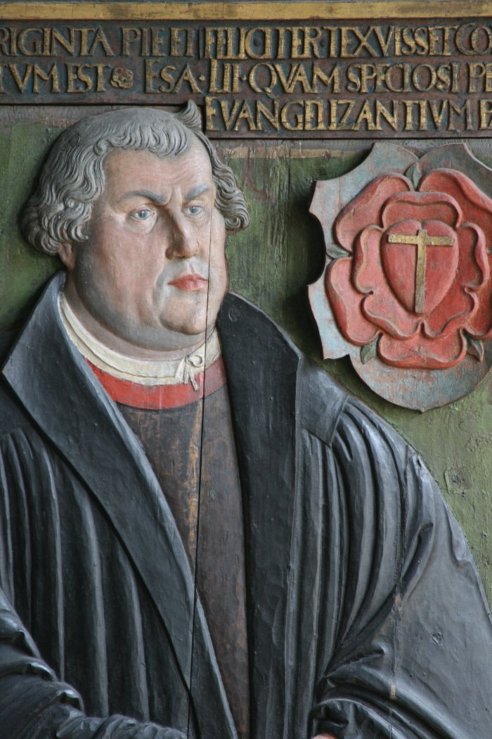 Detail der Grabplatte Luthers Ein Mann in Kutte, über ihm ein Schriftband. rechts die Lutherrose.