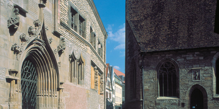 Links im Bild die wiederaufgebaute Universität, rechts ein Teil der Universitätskirche.