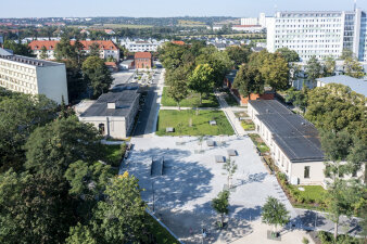 Luftaufnahme eines Parkbereichs mit großer Platzfläche und säumenden Gebäuden