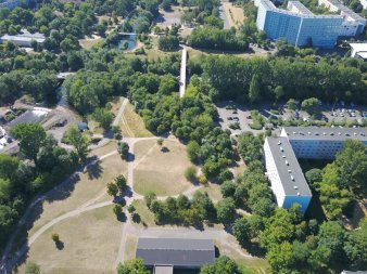 Grün- und Waldflächen mit Wegen neben Plattenbaugebiet