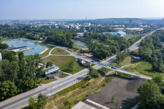 Luftaufnahme einer Straße, über die eine Brücke verläuft, eine Parklandschaft schließt sich an