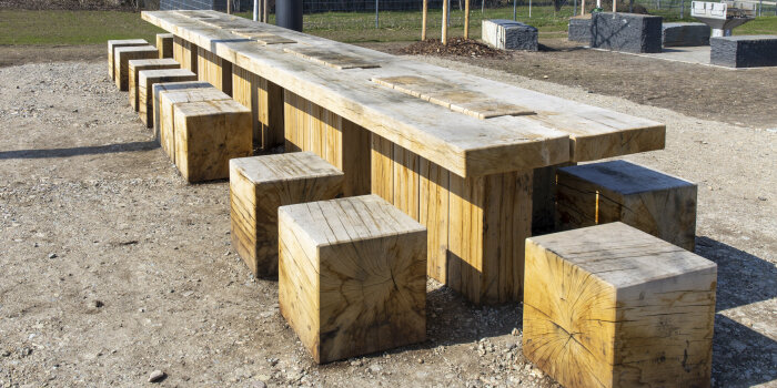 ein großer Holztisch mit Sitzhockern in einem Park