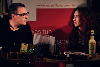 Carsten Rose und Dr. Maria Stürzebecher sitzen an einem Tisch, auf dem verschiedene Pflanzuntensilien liegen.