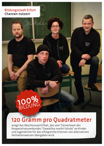 Vier Anti-Aggressivitätstrainer sitzen auf einem Tisch in einem Klassenraum. Darunter steht der Satz: "120 Gramm pro Quadratmeter wiegt das Abschlusszertifikat, das vom Trainerteam des Kooperationsverbundes "Gewaltlos macht Schule" an Kinder und Jugendliche für das erfolgreiche Erlernen von alternativen Verhaltensweisen übergeben wird."