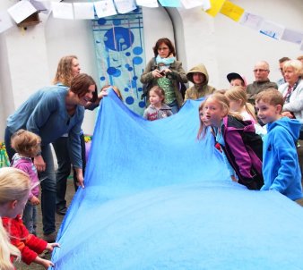 Lehrkräfte und Kinder mit Tüchern beim Wasserfest im Schulhof im Vorjahr