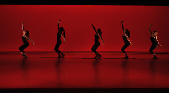 Tänzerinnen auf rot erleuchteter Bühne.
