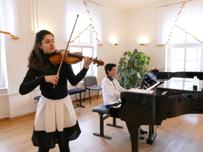 Musikschüler spielen für die Ukraine Mädchen mit Violine und Junge am Klavier
