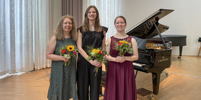 drei Personen Personen mit Blumenstrauß in der Hand vor einem Klavier