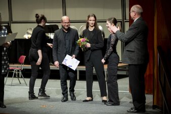 vier Personen in Reihe, ein Mann steht davor und applaudiert