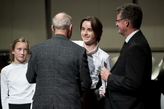 drei Personen nehmen von einem Mann im Sakko Gratulationen entgegen