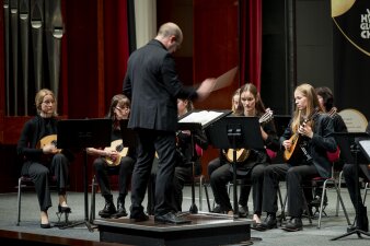 ein schwarz gekleidetes Zupforchester mit Dirigent auf der Bühne