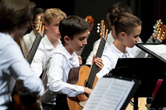 junge Mitglieder eines Gitarrenrorchesters mit weißen Hemden beim Vorspiel