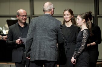 ein Mann gratuliert einem Mann und zwei Mädchen