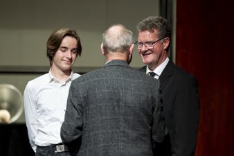 zwei Personen nehmen von einem Mann im Sakko Gratulationen entgegen